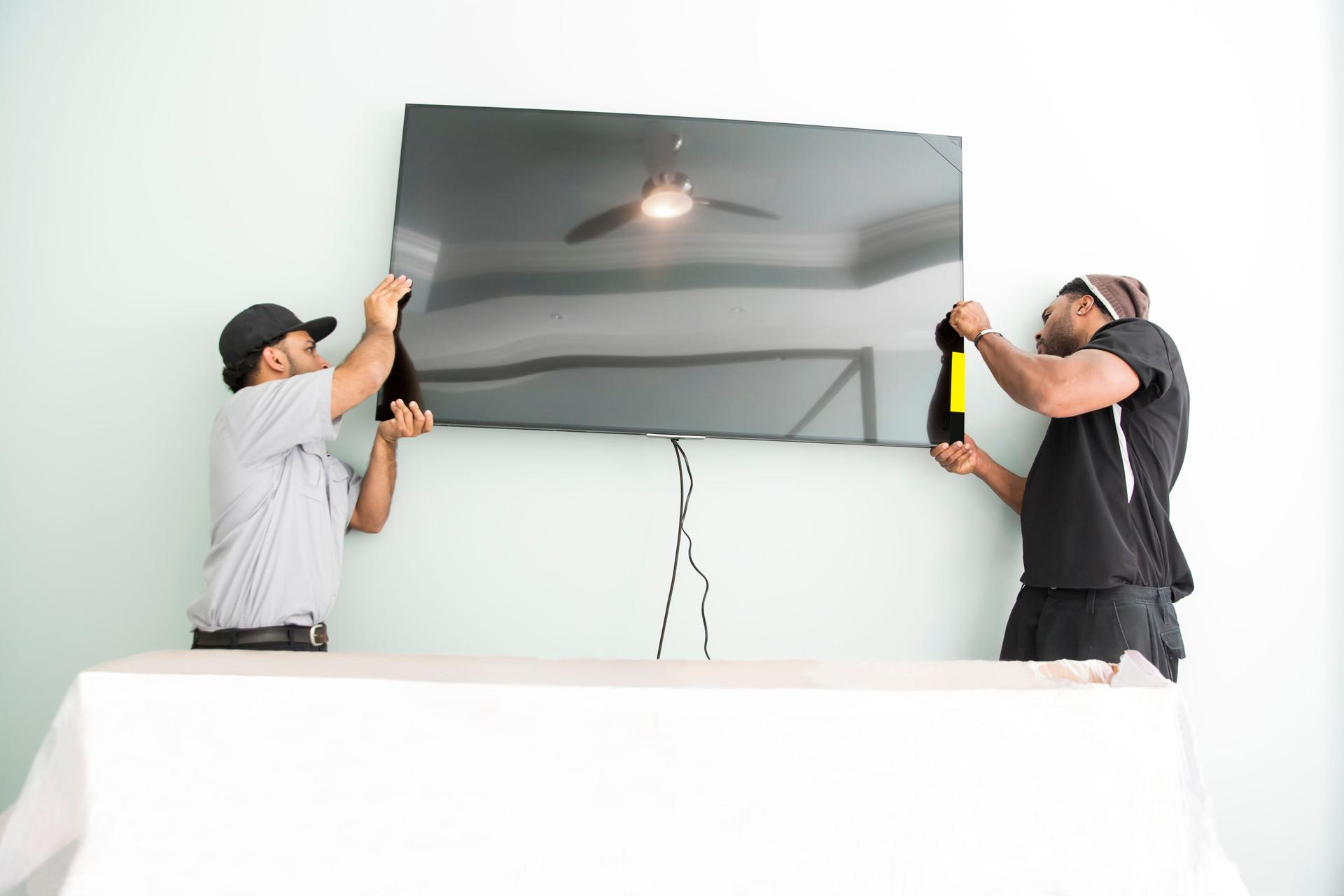 Series-Real televison installers hanging large flat screen TV on wall