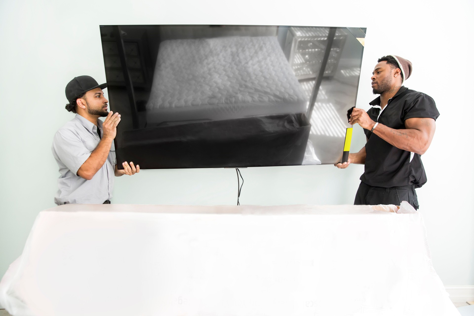 Series-Real televison installers hanging large flat screen TV on wall