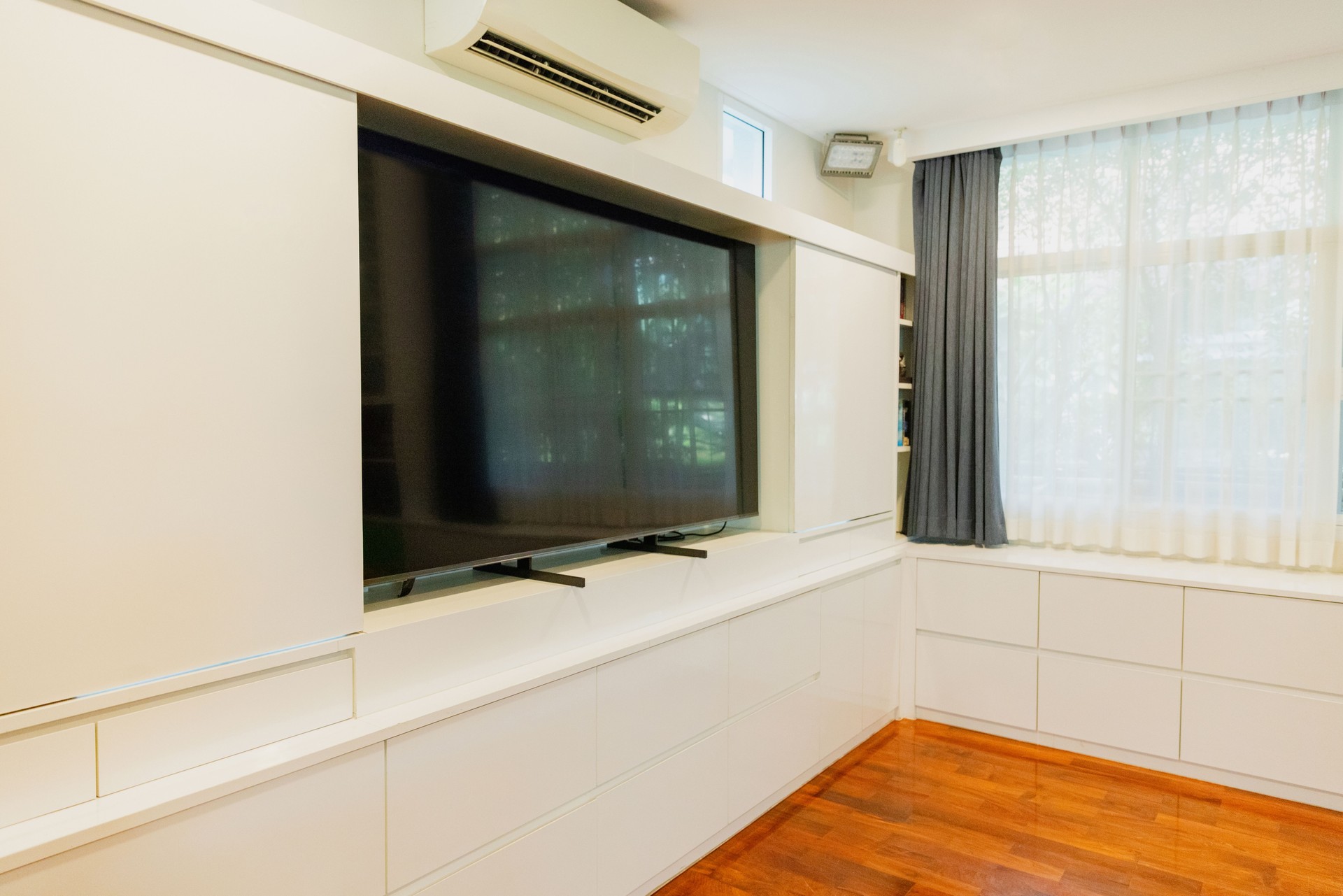 Modern living room featuring a large television and minimalist design with natural light