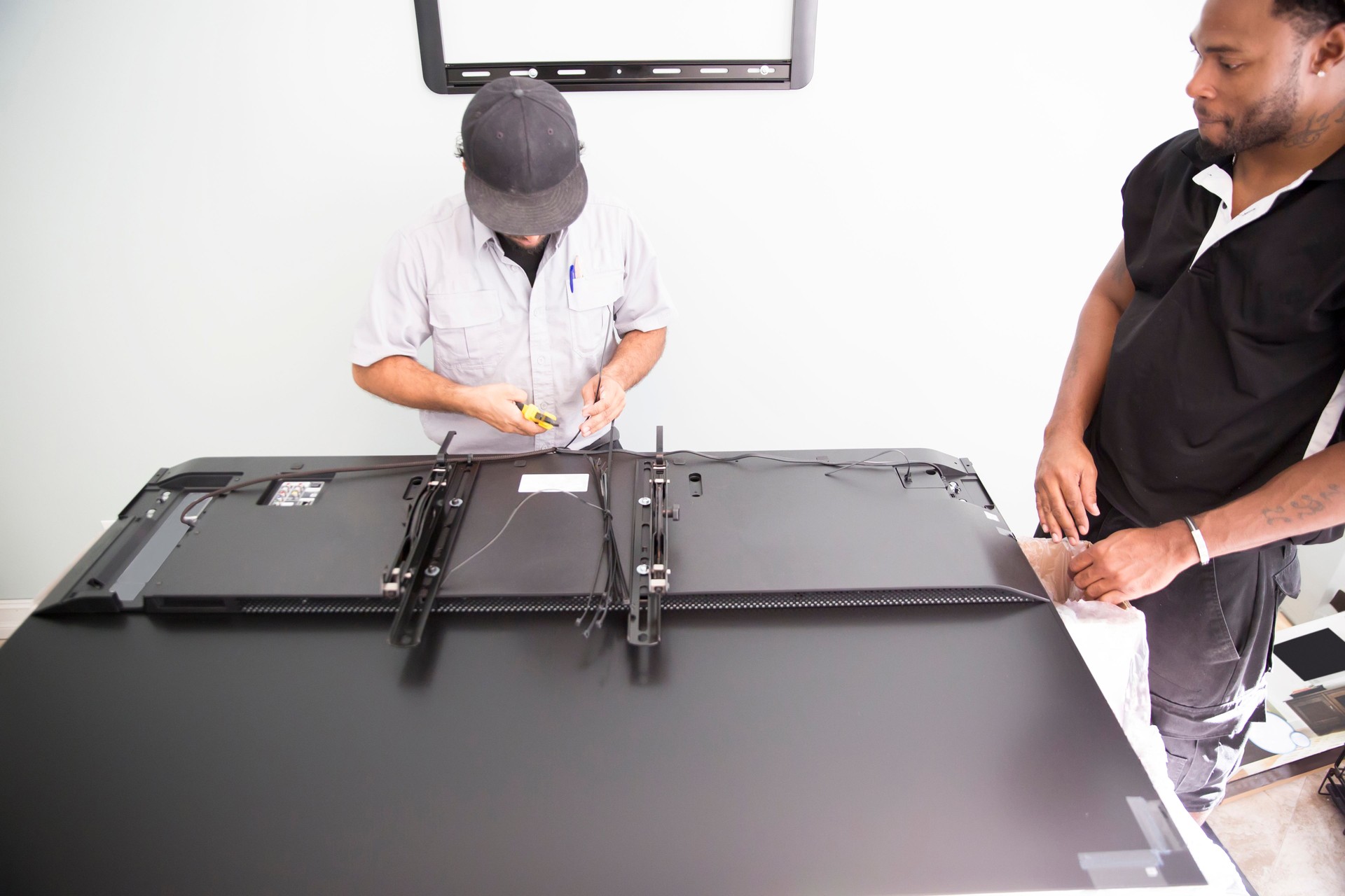 Series-Real televison installers handing large flat screen TV in wall